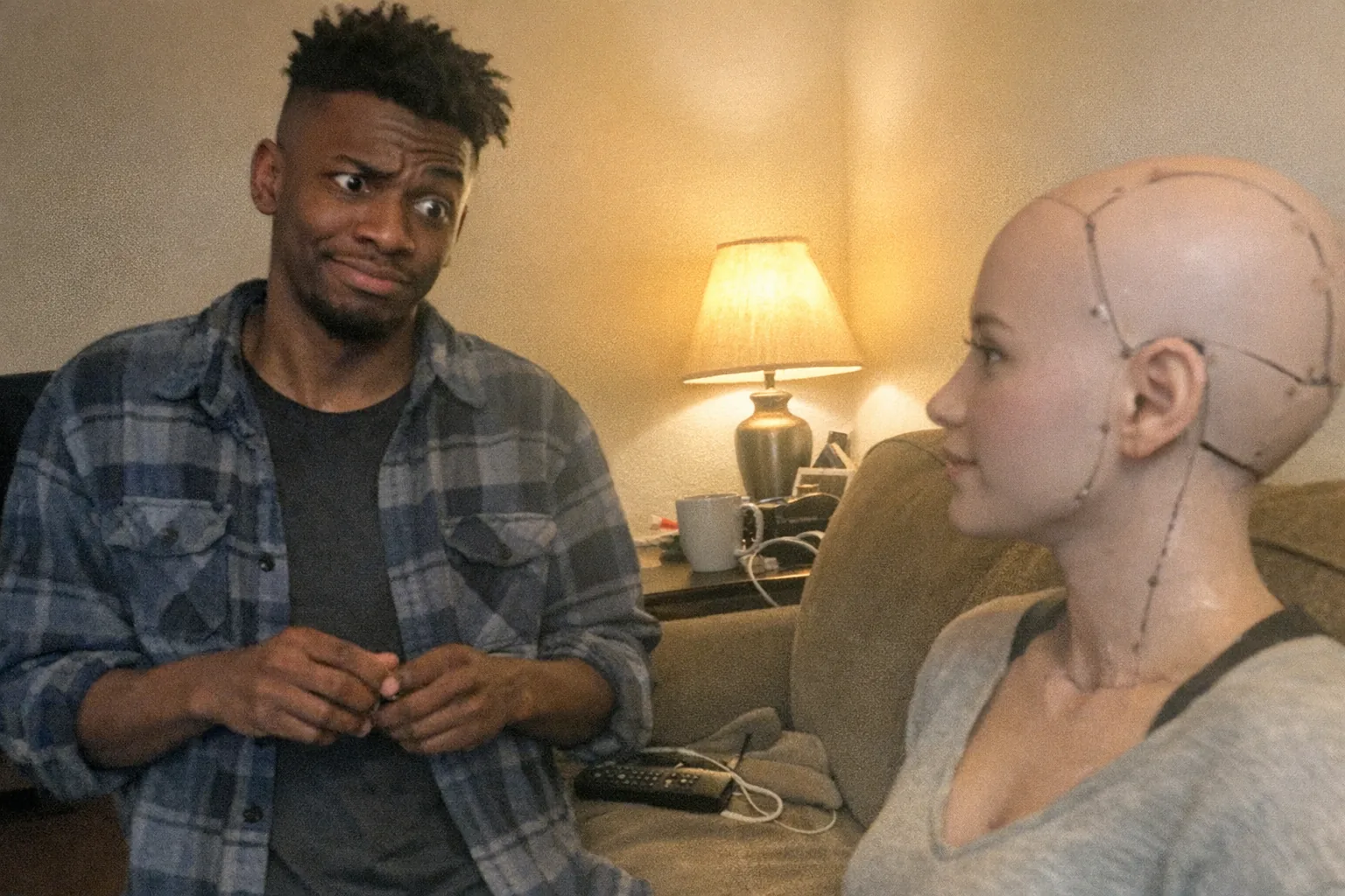 A candid iPhone snapshot in a modest apartment living room at night: a mid-20s Black man with dark brown skin, slim build, undercut with textured top, wearing a slightly worn flannel shirt (blue-collar look), standing near a couch and looking skeptical and surprised (raised eyebrow, wide eyes, half-smirk) while fidgeting with his hands. On the couch sits a female-presenting companion robot (humanoid head-and-shoulders form with a simple silicone-like face and visible seams, non-explicit), slightly turned toward him as if listening. Awkward framing with the robot partially cut off, slight motion blur, mildly overexposed warm lamp lighting with uneven shadows, natural phone noise/grain, aggressively mediocre composition, everyday clutter (remote, coffee mug, charging cable) visible. No text, no logos, no watermarks.